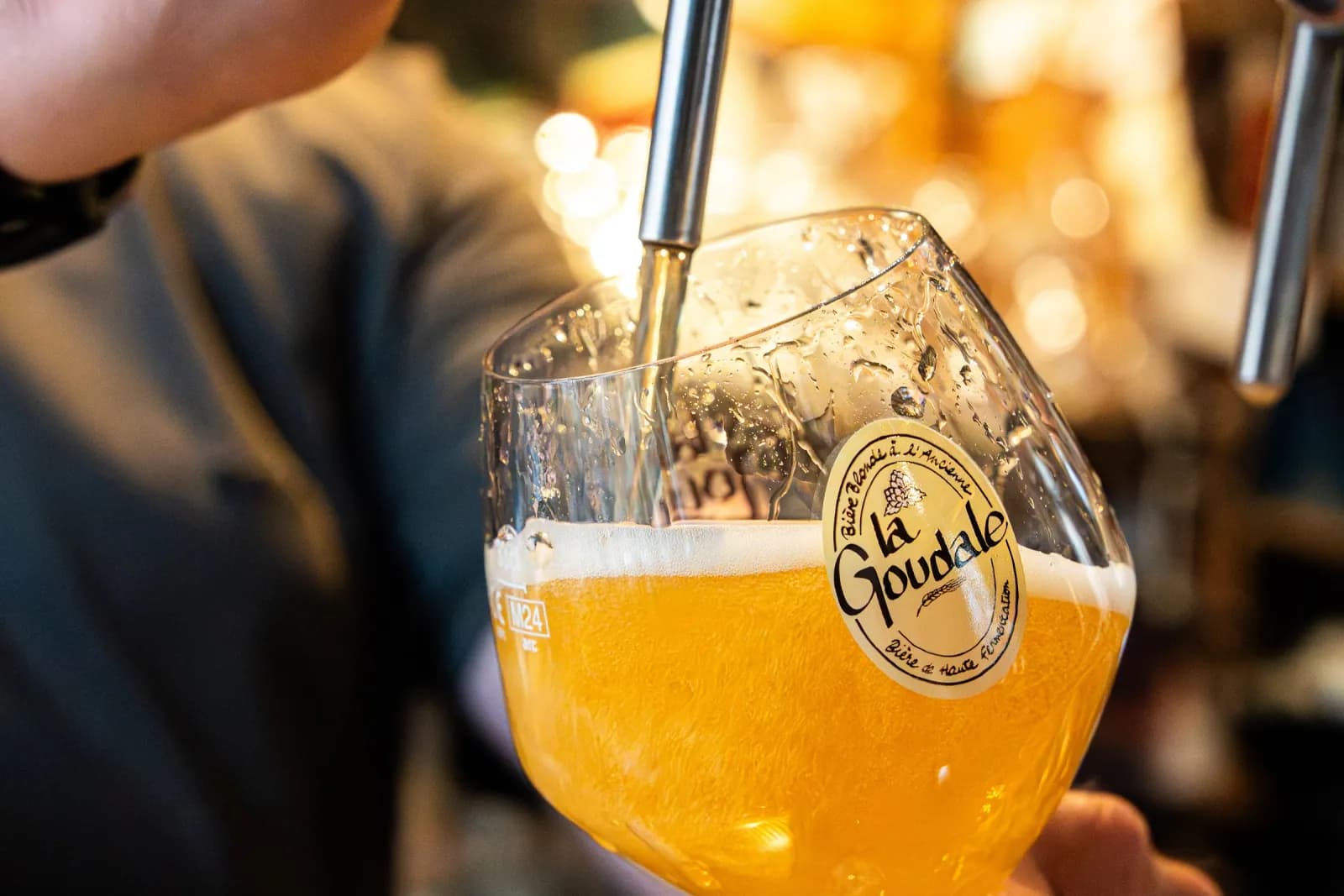Une bière blonde tirée à la pression dans un verre calice, incliné sous le bec.