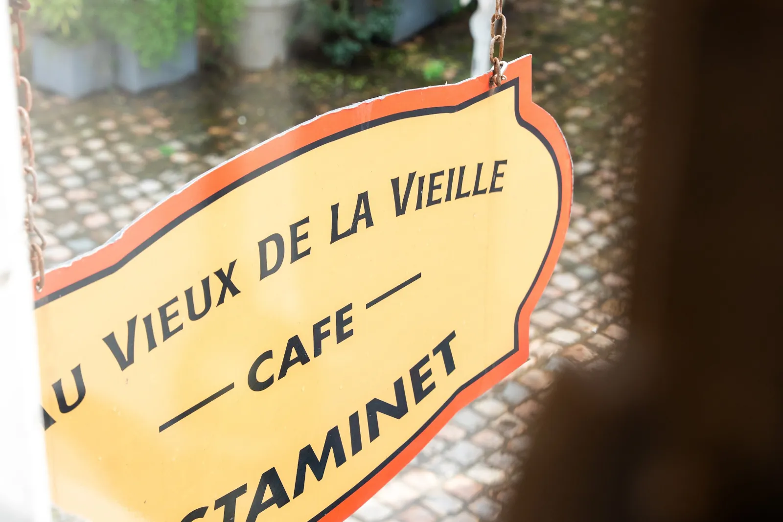 El rótulo de Au Vieux de la Vieille, café estaminet, visto desde el interior a través del cristal.
