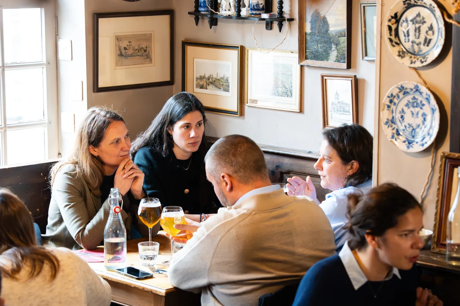 Une salle claire, assiettes en faïence accrochées au mur et houblon séché au plafond.