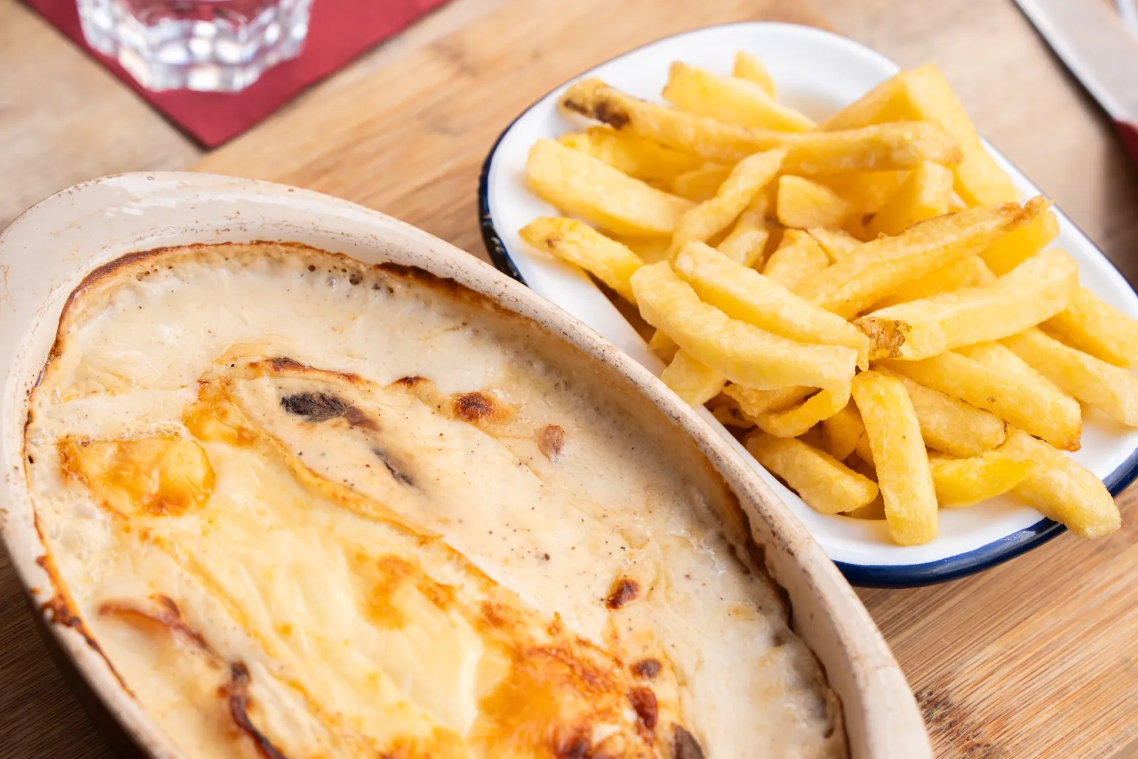 Un welsh dans son plat ovale, vu de dessus, avec sa coupelle de frites fraîches.